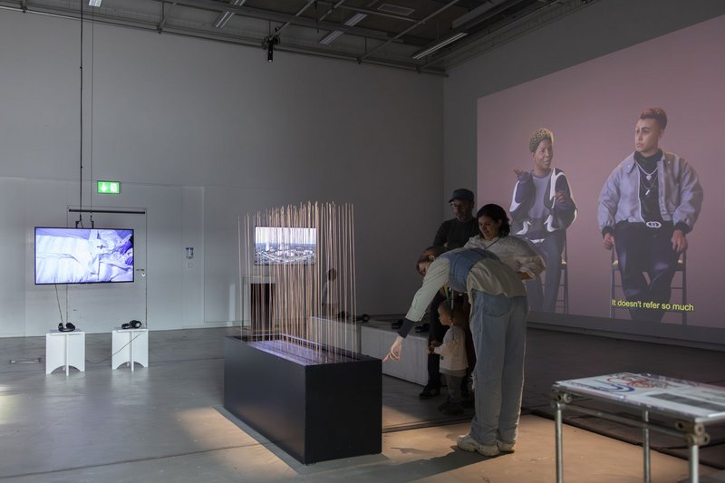 Ausstellung im Aktionsraum. Auf die rechte Wand wird ein Film projiziert. Es steht ein Exponat mitten im Raum. © David Jäggi.