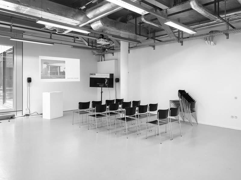 LECTURE ON RAFAEL ALCAMPO BY SIYLVIA P- GREENWOOD 2025 Einkanal-Video auf Monitor (Farbe, Ton, 20 Min.), Projektion (Diashow, 17 Min.); Stühle, Sockel Variable Dimensionen  Performance: Lecture on Rafael Alcampo by Sylvia P. Greenwood, 2025, 20 min