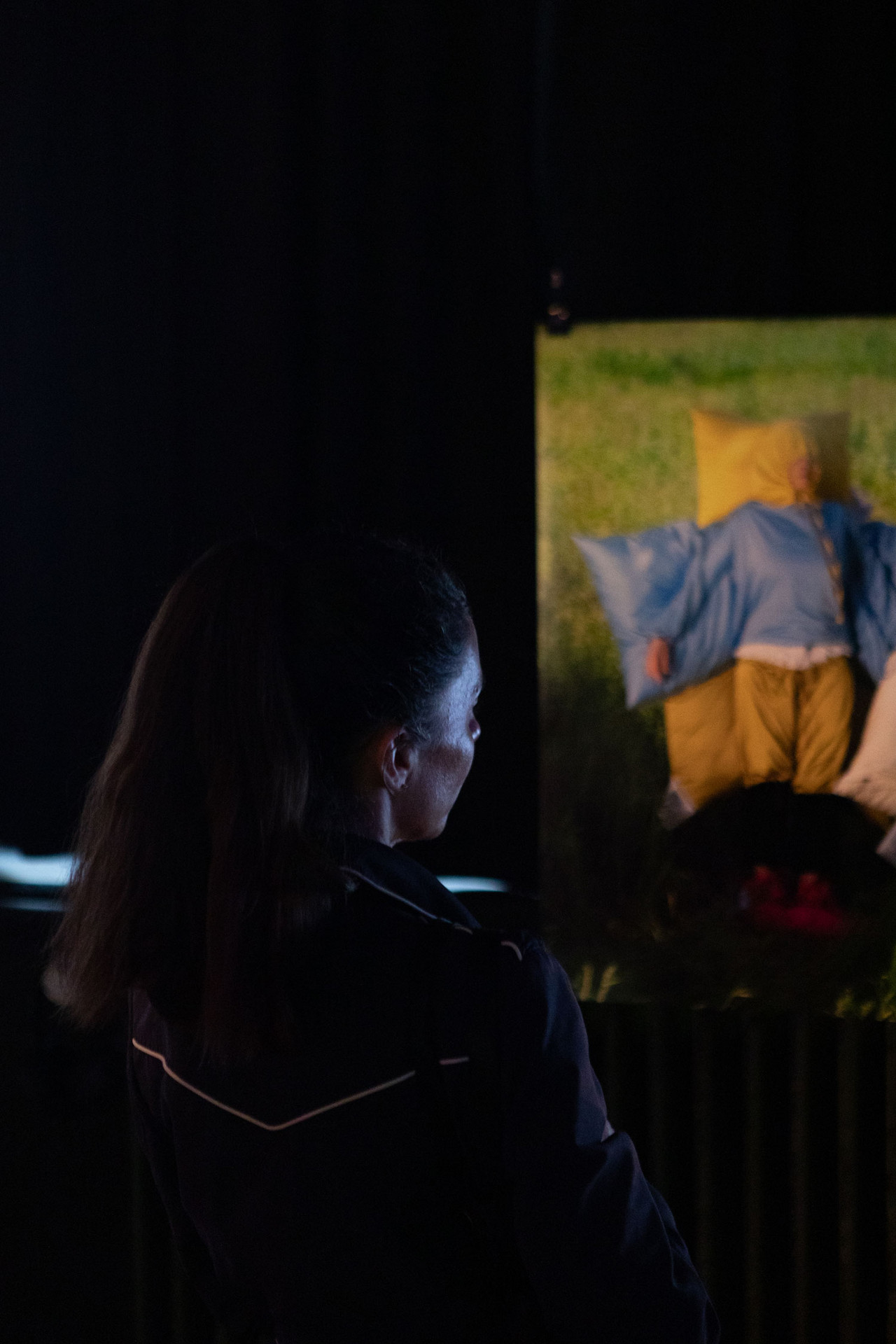 Eine Person sieht sich ein Bild an: Darauf liegt eine Person auf Kissen und wird fast von ihnen umhüllt.