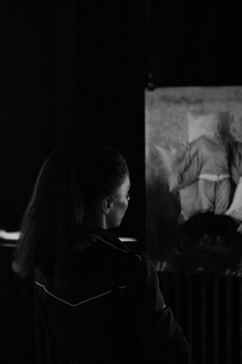 Eine Person sieht sich ein Bild an: Darauf liegt eine Person auf Kissen und wird fast von ihnen umhüllt.