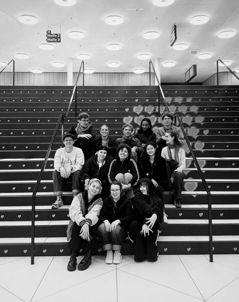 Cast students sitting on stairs with the ESC logo (many little hearts) dem ESC-Logo. Credits: Nadia Holdener.