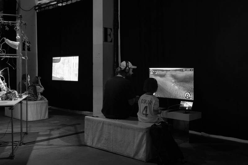 Besuchende vor zwei Screens - einem Film und einem Videospiel.