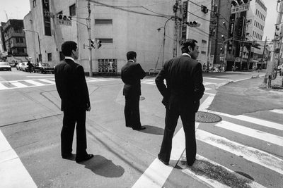 Alberto Venzago, Drei Bodyguards sichern die Kreuzung für den Boss, Stadtteil Ikebukuro, Tokyo, Japan, 1988, © Alberto Venzago