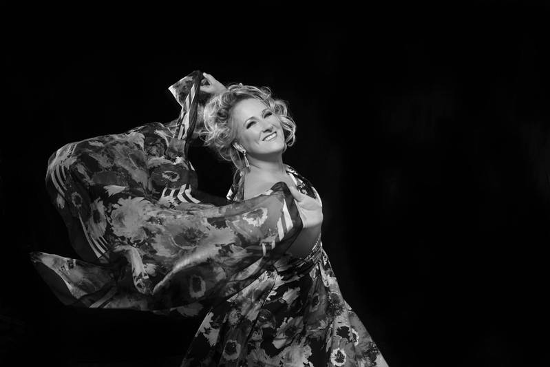 Eine strahlende Frau, umhüllt von ihrem geblümten Foulard, tanzt
